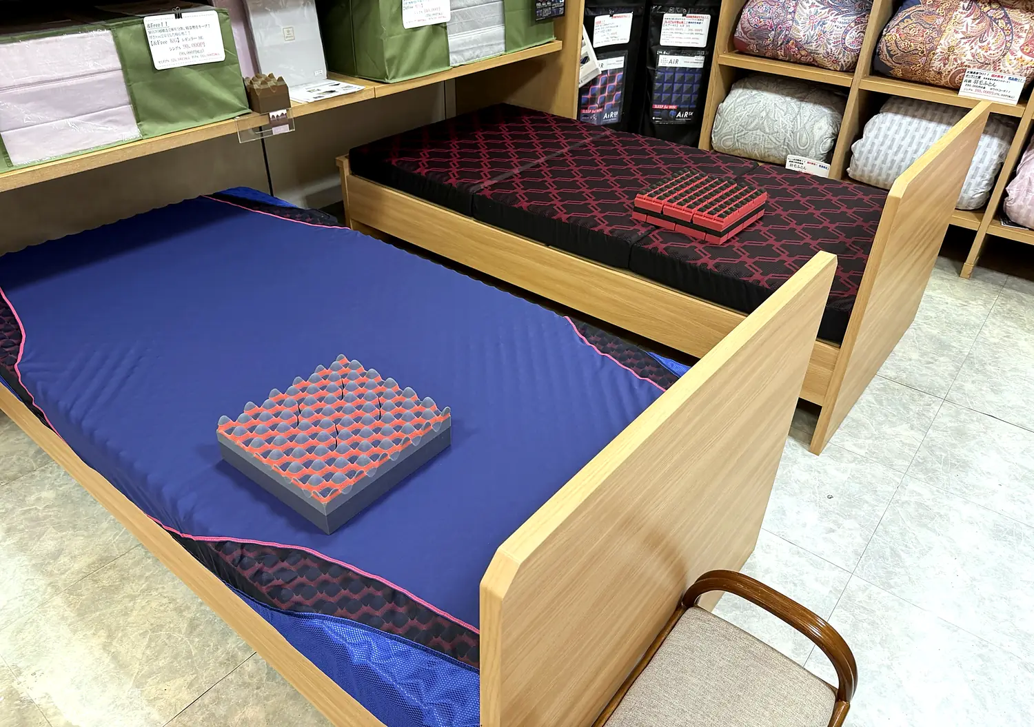 店内の体験ベッド。赤いマットレスと青いマットレスの上に、中身の断面サンプルが置かれている